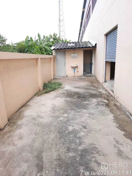 工厂 出租在Bang Bua Thong, Nonthaburi - 侧院混凝土通道，设有洗手池、围墙和出入口。