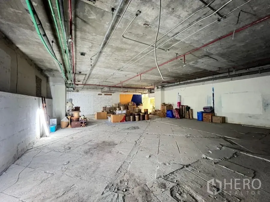 Retail Space for rent - Expansive unfinished commercial space with exposed ceiling lines and scattered cartons.