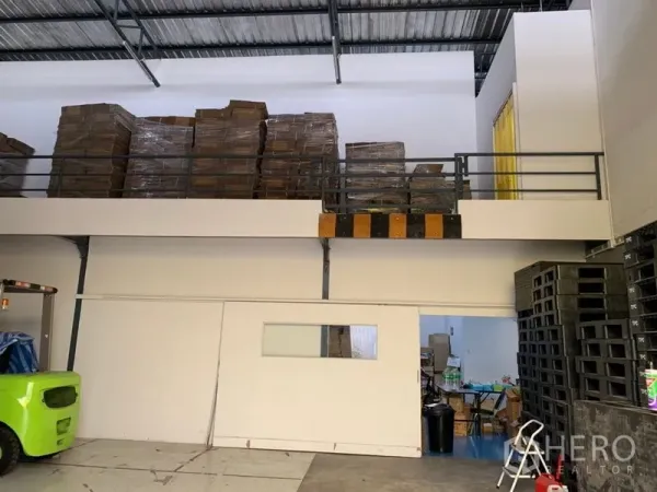 Warehouse for rent in Bang Kapi, Bangkok - Mezzanine level with safety railings used for pallet storage beneath a high steel roof.