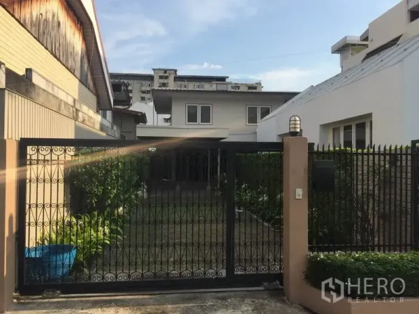 บ้าน ให้เช่าในKhlong Toei, Bangkok - มุมมองหน้าบ้านเดี่ยว พร้อมรั้วเหล็กดัดและสนามหญ้าจัดแต่ง