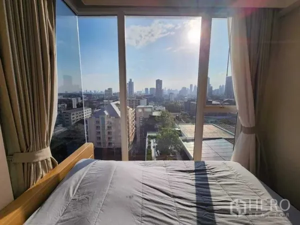 Condominium for rent in Khlong Toei, Bangkok - City skyline view from bedside through large glass windows with morning sun.