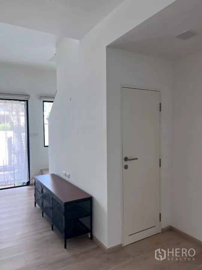 Townhouse for rent in Bang Phli, Samut Prakan - Entry hall with white interior door and low media cabinet beside the stairs.