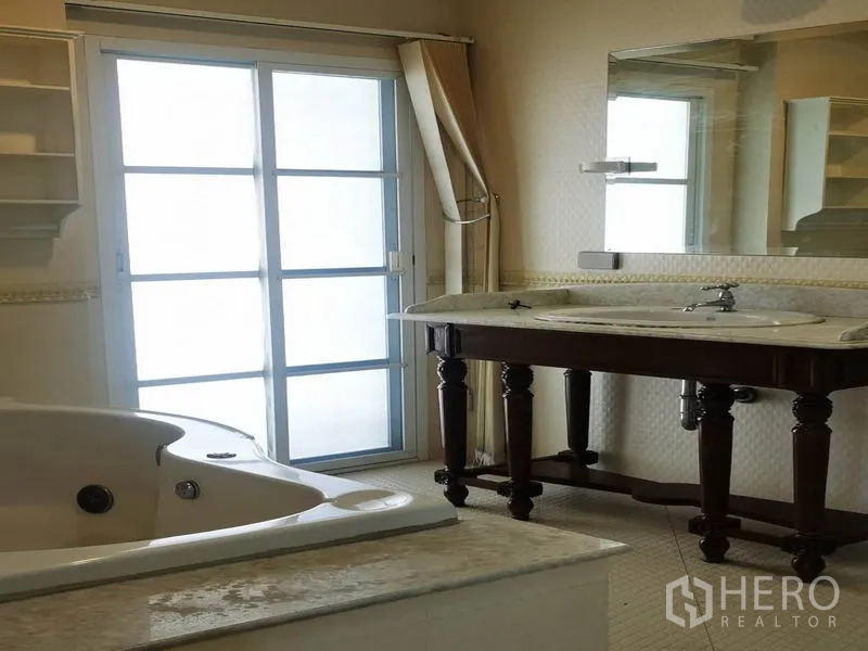 Detached House for rent in Mueang Samut Prakan, Samut Prakan - Bathroom with jetted bathtub, large vanity and sliding glass door to a balcony or terrace.