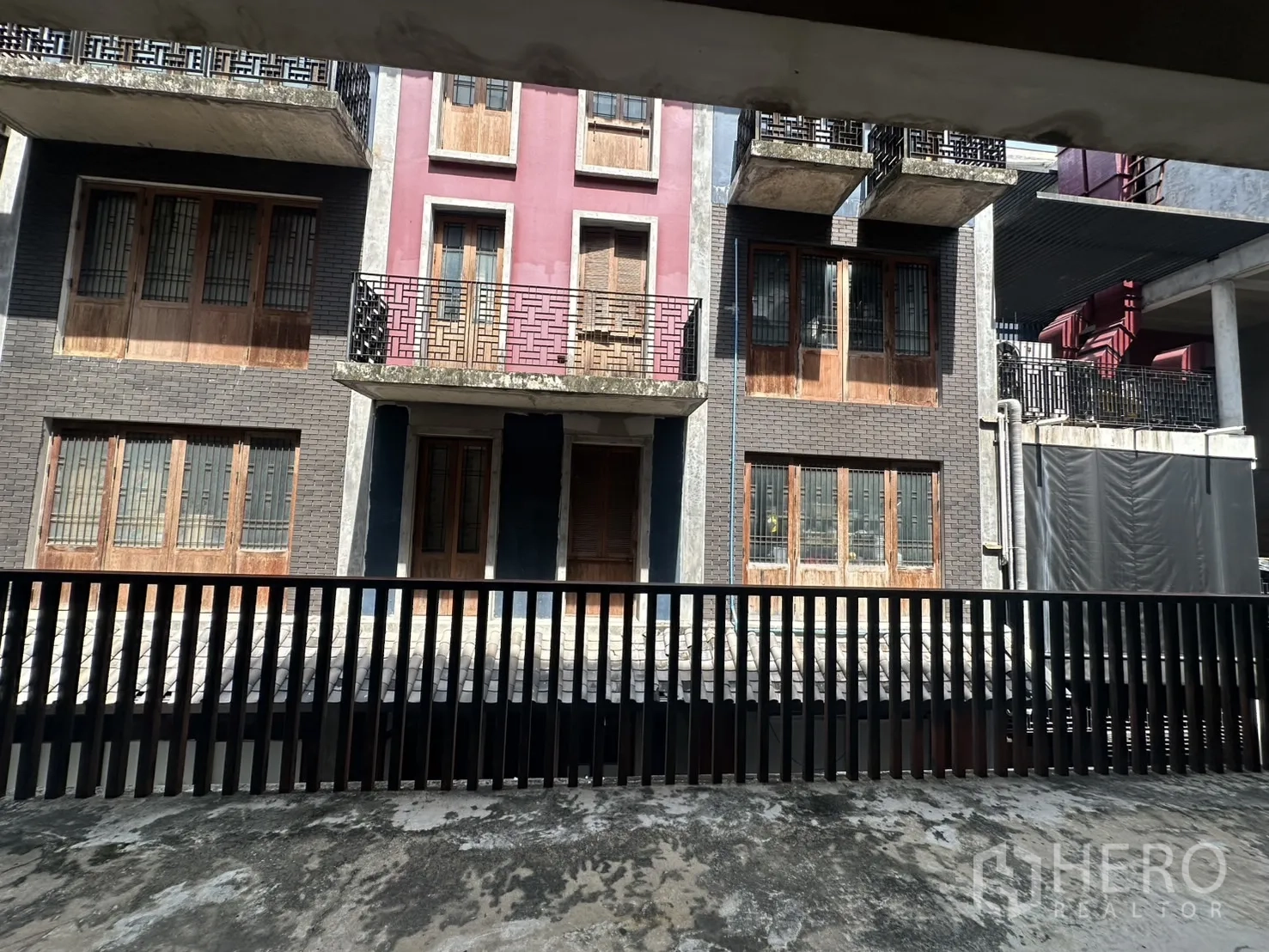 Home Office for rent in Pathum Wan, Bangkok - Balcony view across low-rise shophouse-style buildings with a metal railing in the foreground.
