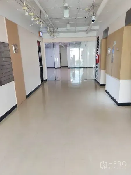 Office Space for rent in Pathum Wan, Bangkok - Bright corridor in an office building with glass partitions, suspended lighting and polished floors.