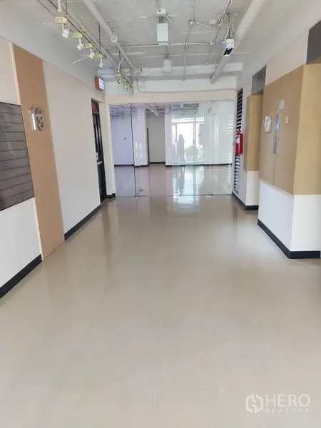 Office Space for rent in Pathum Wan, Bangkok - Bright corridor in an office building with glass partitions, suspended lighting and polished floors.
