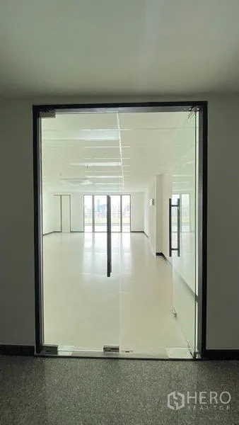 Office Space for rent in Watthana, Bangkok - Glass double doors open to a bright open-plan office with white walls and a dropped ceiling.