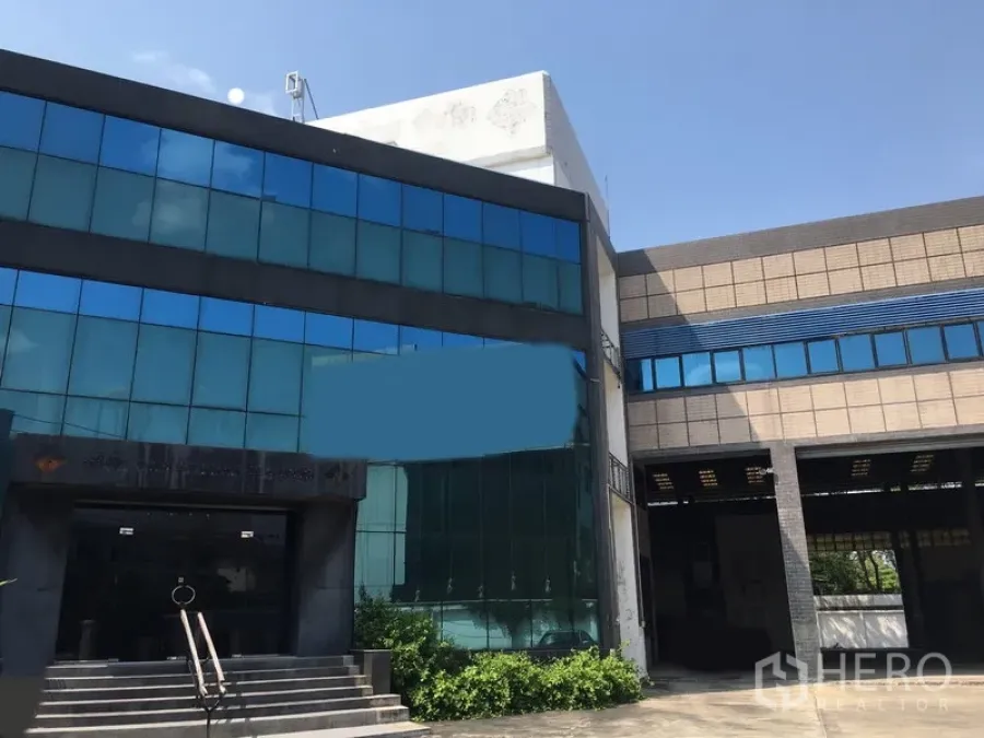 Warehouse for rent or sale in Bang Kapi, Bangkok - Glass-front office building connected to the warehouse with covered loading entrance.