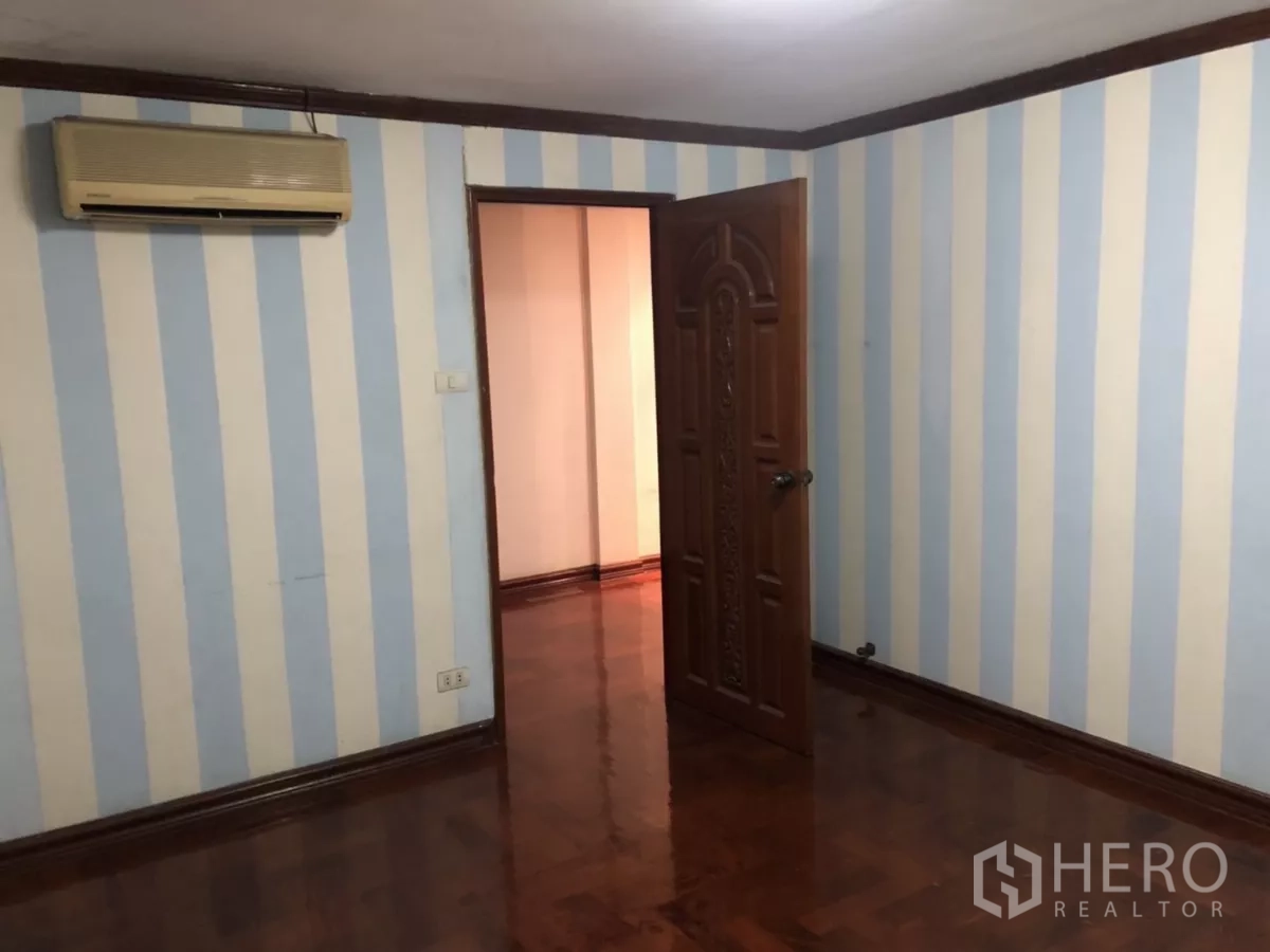 带办公室的家 出租在Phra Khanong, Bangkok - 卧室带蓝白条纹墙、木门与壁挂空调。