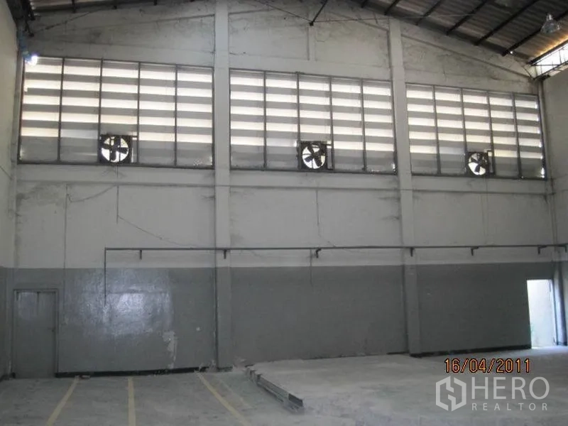 工厂 出租在Bang Sao Thong, Samut Prakan - 高挑厂房内部，百叶通风窗与排风扇、混凝土地面。