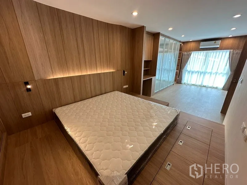 Home Office for rent in Khlong Toei, Bangkok - Spacious master bedroom with wood panel feature wall, platform bed and floor-to-ceiling windows.