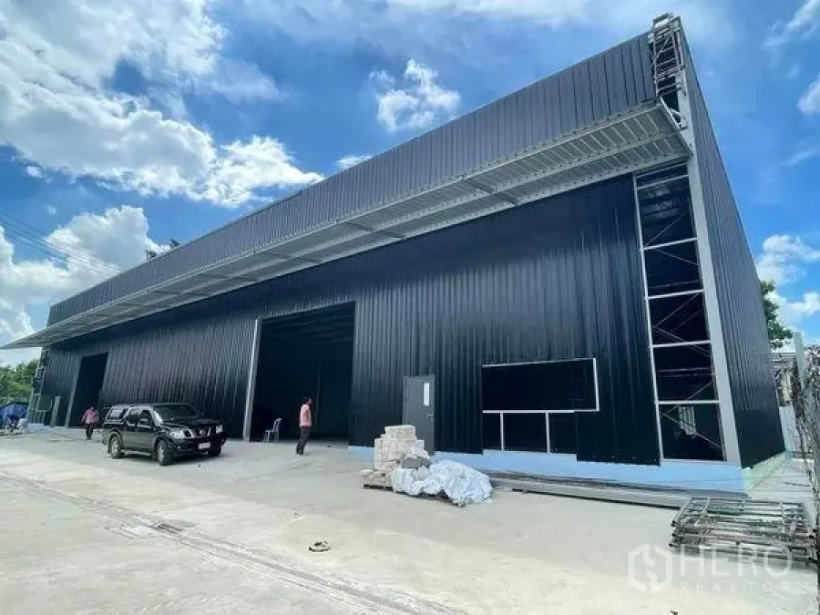 Warehouse for rent in Pak Kret, Nonthaburi - Modern black metal warehouse exterior with tall canopy and wide loading bays in Pak Kret, Nonthaburi.