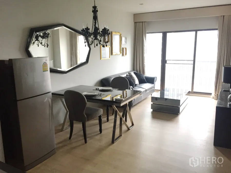 Condominium for rent in Bangkok - Bright living and dining area with chandelier, large wall mirror, sofa, dining table and sliding doors to the balcony.