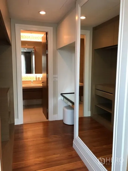 Condominium for rent or sale in Khlong Toei, Bangkok - Walk-in closet corridor with full-height mirror leading to the bathroom.