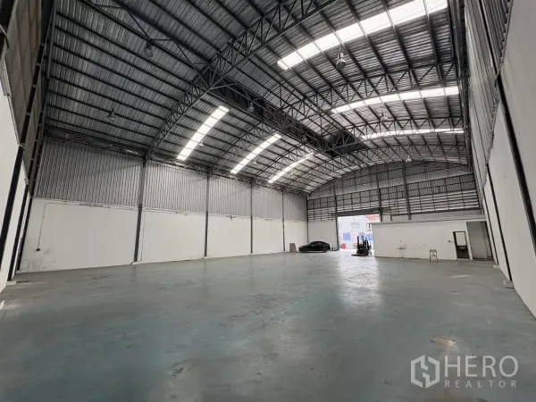 Warehouse for rent in Bang Phli, Samut Prakan - Large storage floor facing the roller door and office block under a curved roof.