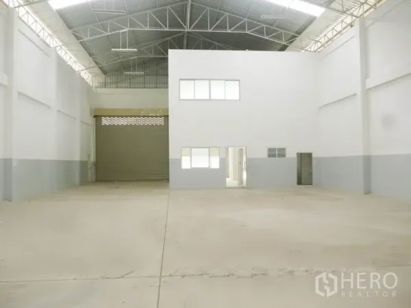 Factory for sale in Pathum Thani - Spacious high-clearance warehouse bay with steel roof, natural light and a roller door.