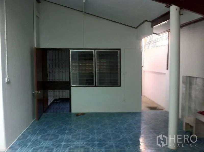 货栈 出租在Lam Luk Ka, Pathum Thani - 罩棚下的杂用区，蓝色地砖、白墙与推拉窗。