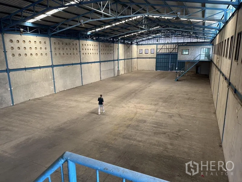 Warehouse for rent in Bang Phli, Samut Prakan - View from the mezzanine overlooking a large unobstructed warehouse floor and rear loading door.