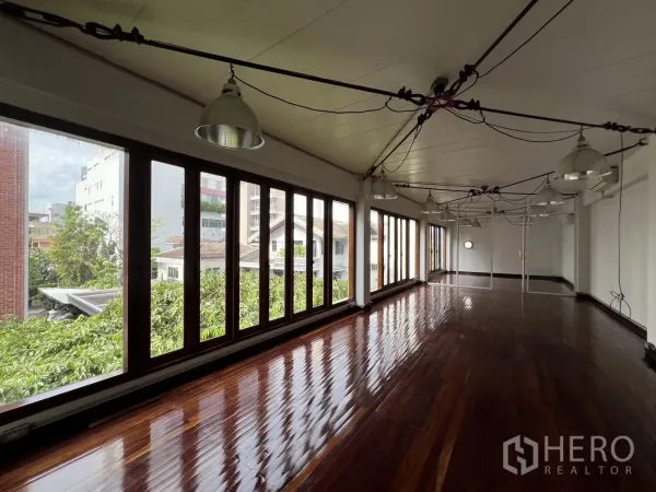 Home Office for rent in Watthana, Bangkok - Open-plan office floor with polished hardwood flooring, a full wall of windows and industrial pendant lighting.