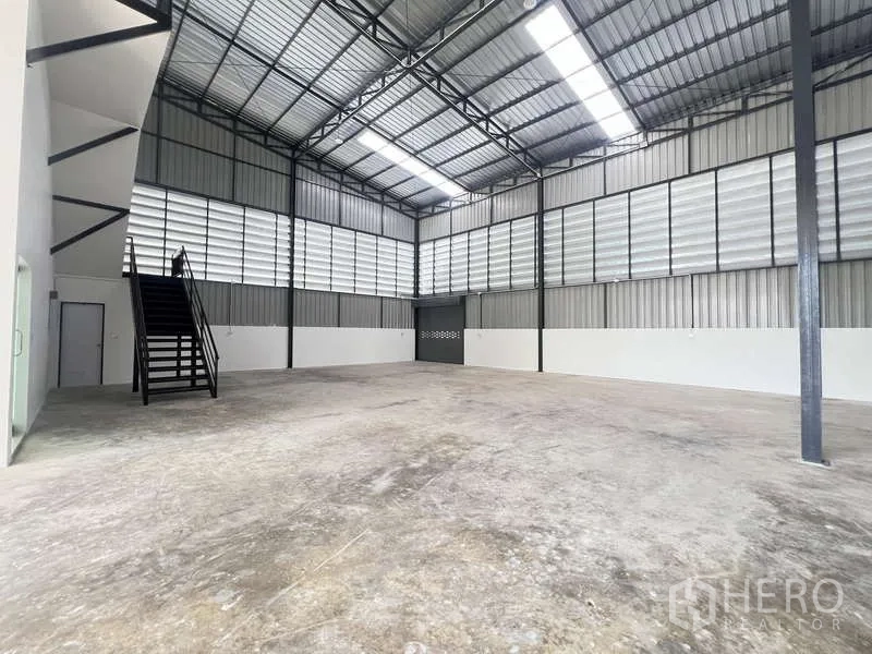 Warehouse for rent or sale - Large warehouse interior with high steel roof, skylights, louvered walls and concrete floor.