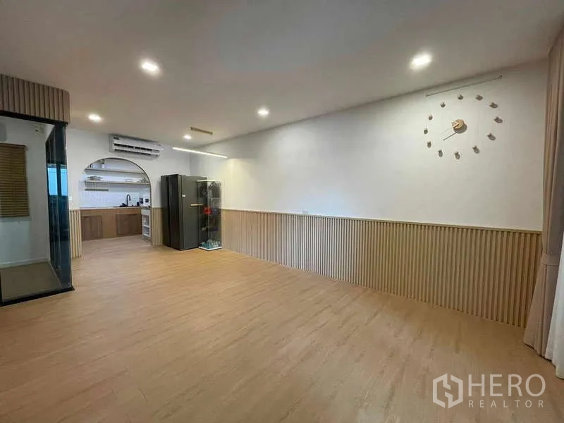 Townhouse for rent or sale in Bang Kapi, Bangkok - Large multipurpose room with wall clock, recessed lights and view to the kitchen.
