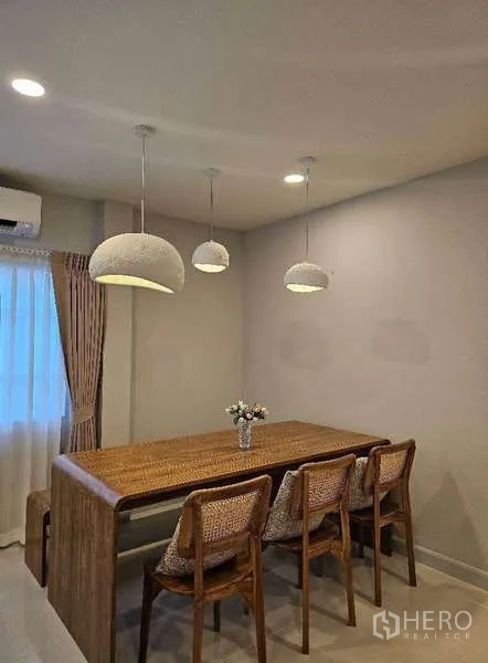 Detached House for rent in Bang Phli, Samut Prakan - Dining area with wooden table for six under pendant lights and curtained window.