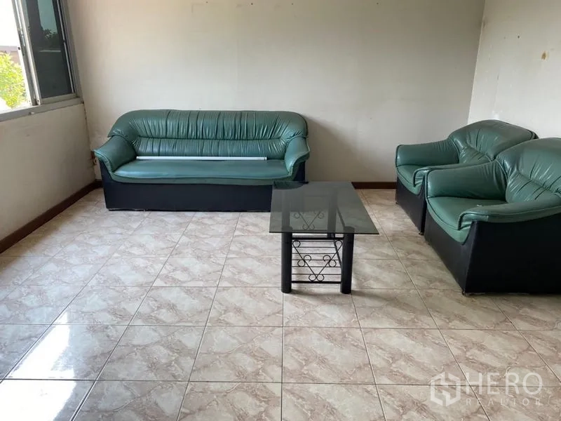 Factory for rent in Lat Lum Kaeo, Pathum Thani - Simple upstairs lounge with green sofas and a glass coffee table.