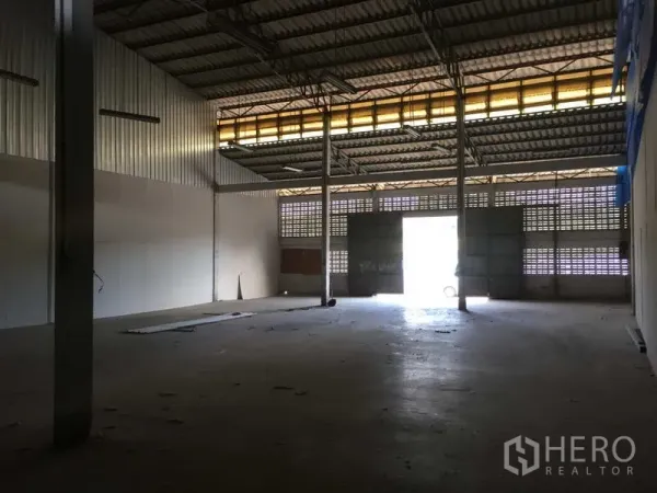 Warehouse for rent in Min Buri, Bangkok - Warehouse interior facing a large sliding door with natural light and ventilation blocks along the walls.