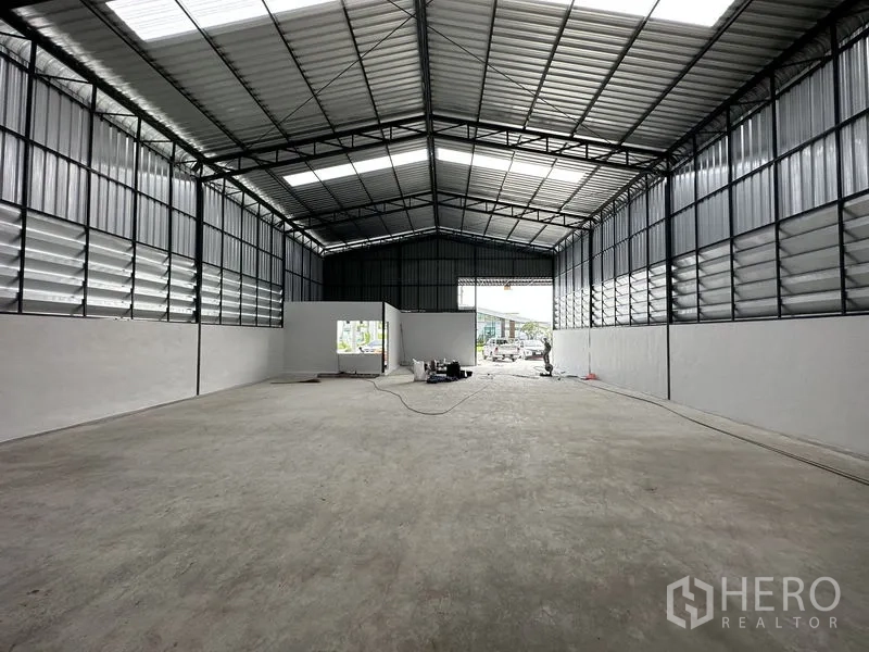 Warehouse for rent in Lam Luk Ka, Pathum Thani - Interior view toward the wide loading opening with polished concrete floors and service points visible.