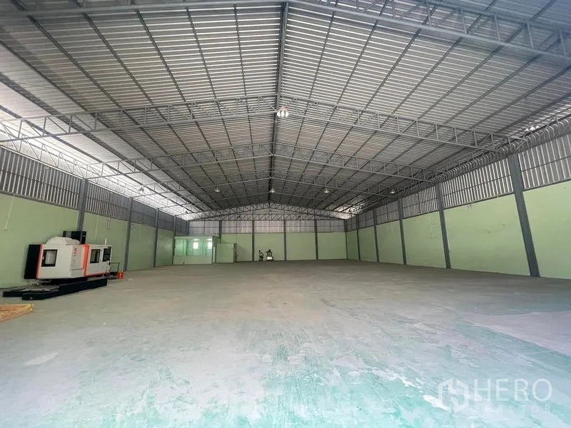 Warehouse for rent in Bang Phli, Samut Prakan - Spacious clear-span warehouse interior with steel truss roof, skylights, and concrete floor.