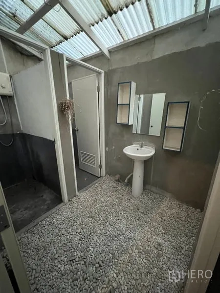 Shophouse for rent or sale in Watthana, Bangkok - Bathroom with translucent skylight roof, pedestal sink and pebble floor.