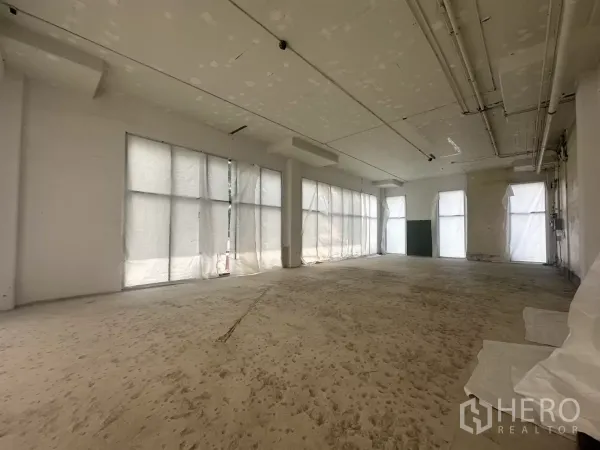 Retail Space for rent in Khlong Toei, Bangkok - Shell-and-core retail interior with high ceiling, exposed services and large window bays.