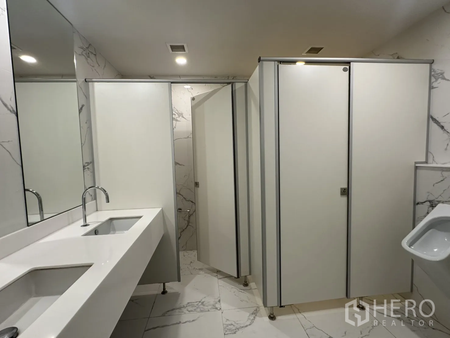 Office Space for rent in Din Daeng, Bangkok - Restroom showing multiple stalls, a urinal, and sleek white countertop sinks.