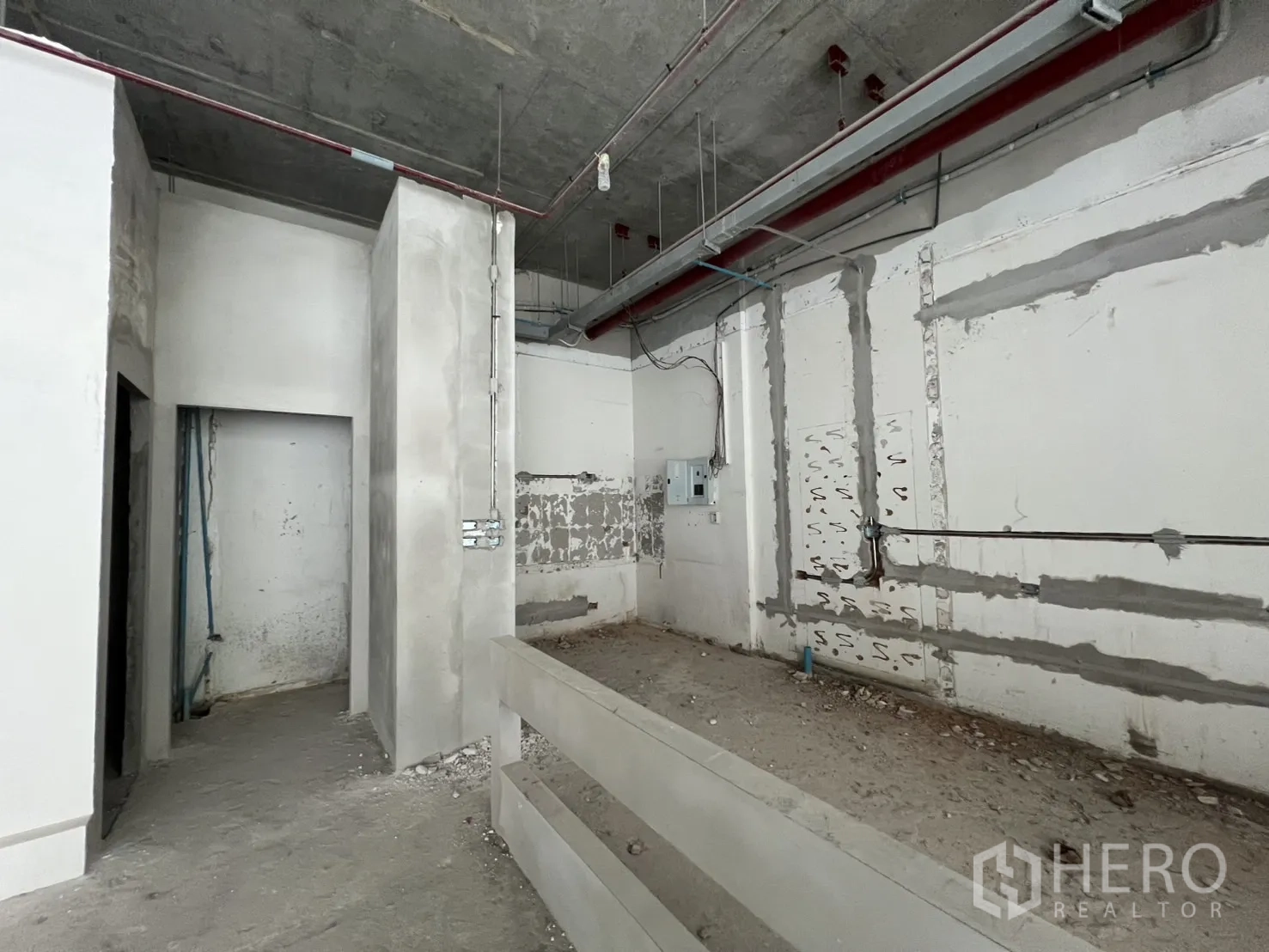 Retail Space for rent in Khlong Toei, Bangkok - Raw concrete retail interior with high ceiling, exposed conduits and partitioned rooms.