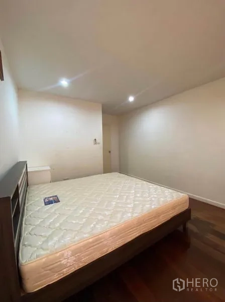 Townhouse for rent in Khlong Toei, Bangkok - Cozy bedroom with double bed, recessed lighting, and wooden floors.