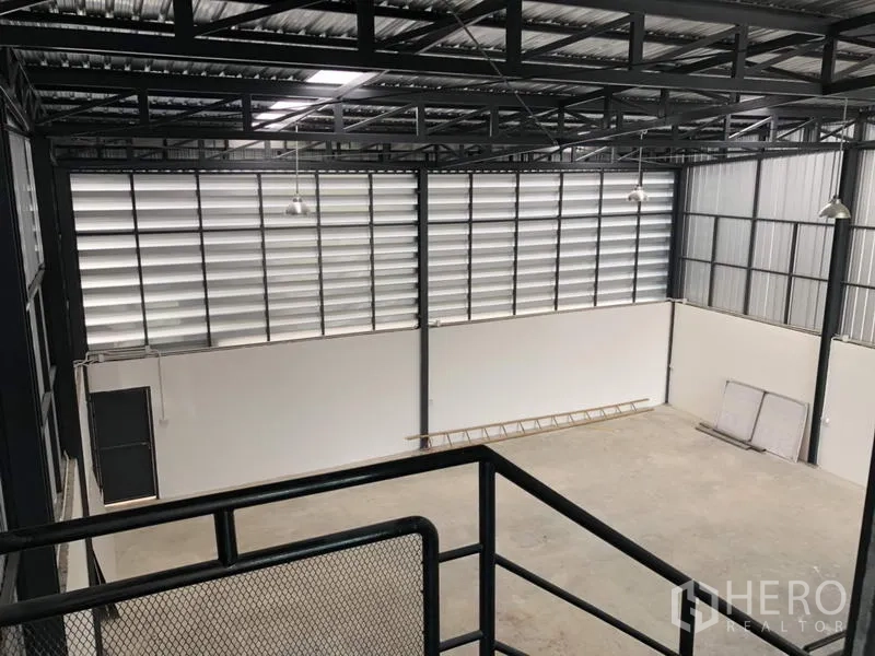 Factory for rent or sale in Lam Luk Ka, Pathum Thani - High-bay warehouse interior with steel trusses, louvered windows, and bright lighting.