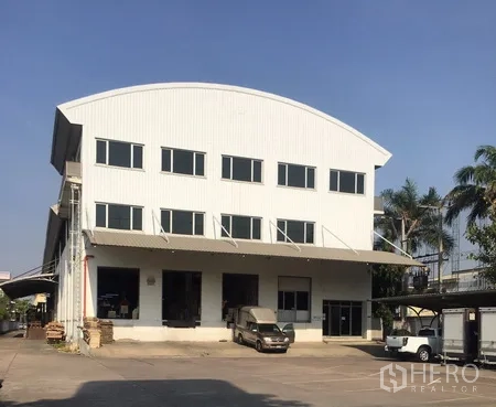 Warehouse for rent in Bang Phli, Samut Prakan - Large modern warehouse exterior with office windows and multiple loading bays in Bang Phli.
