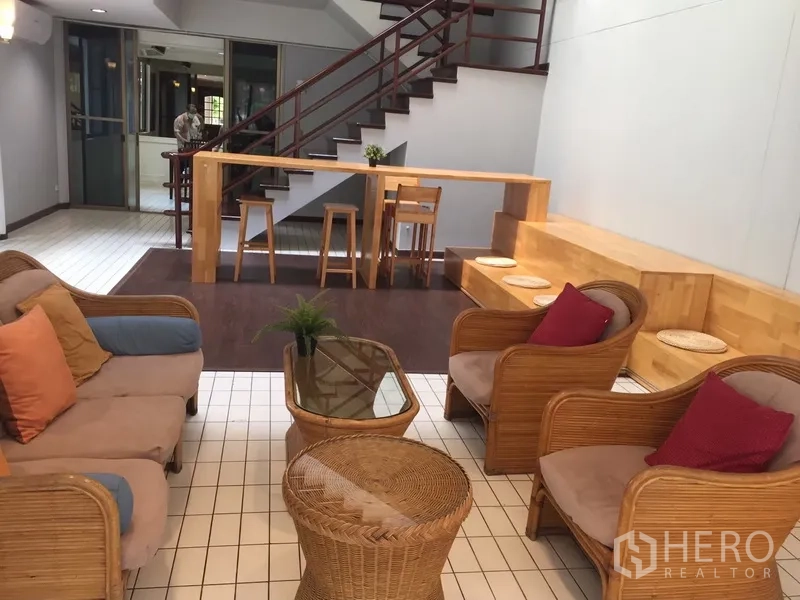 Townhouse for rent in Watthana, Bangkok - Cozy lounge with rattan sofas, bar counter and tiled floors.