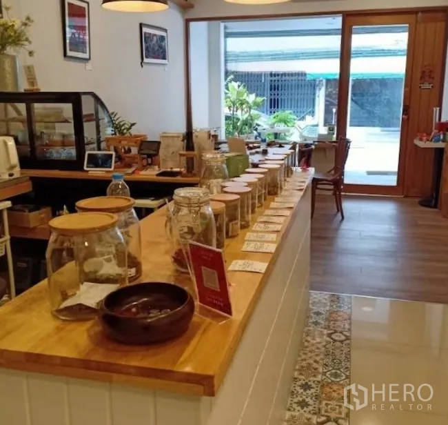 店屋 出租在Watthana, Bangkok - 木质吧台近景，陈列罐沿吧台排列，面向玻璃门店。