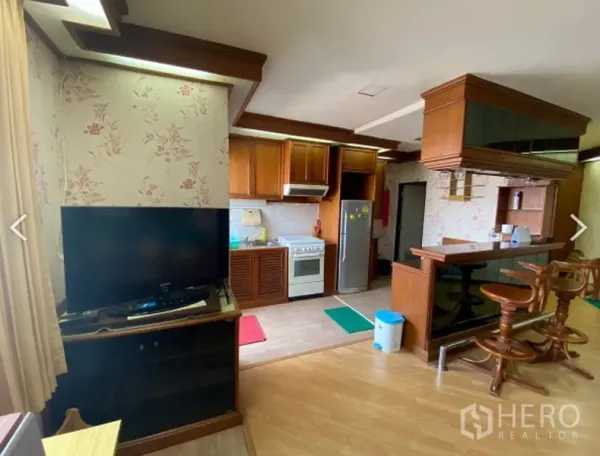 Condominium for sale in Watthana, Bangkok - Living and kitchen area with TV corner, wooden bar counter and fitted cabinetry in D.S. Tower 2 condominium.