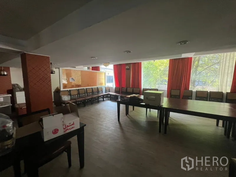 Retail Space for rent or sale in Khlong Toei, Bangkok - Large function room with long benches, curtains and windows overlooking trees.