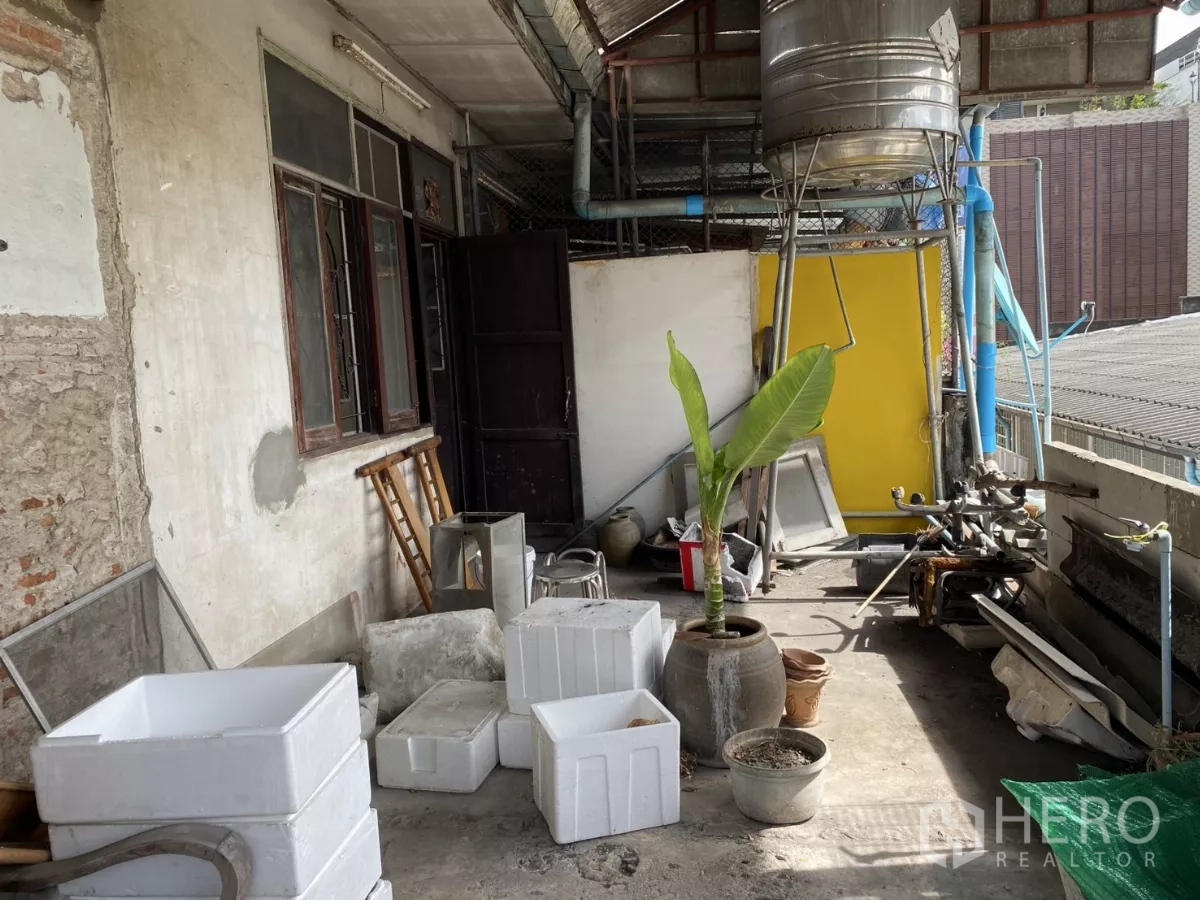 Shophouse for rent in Khlong Toei, Bangkok - Rooftop service area with water tank, planters and concrete flooring.
