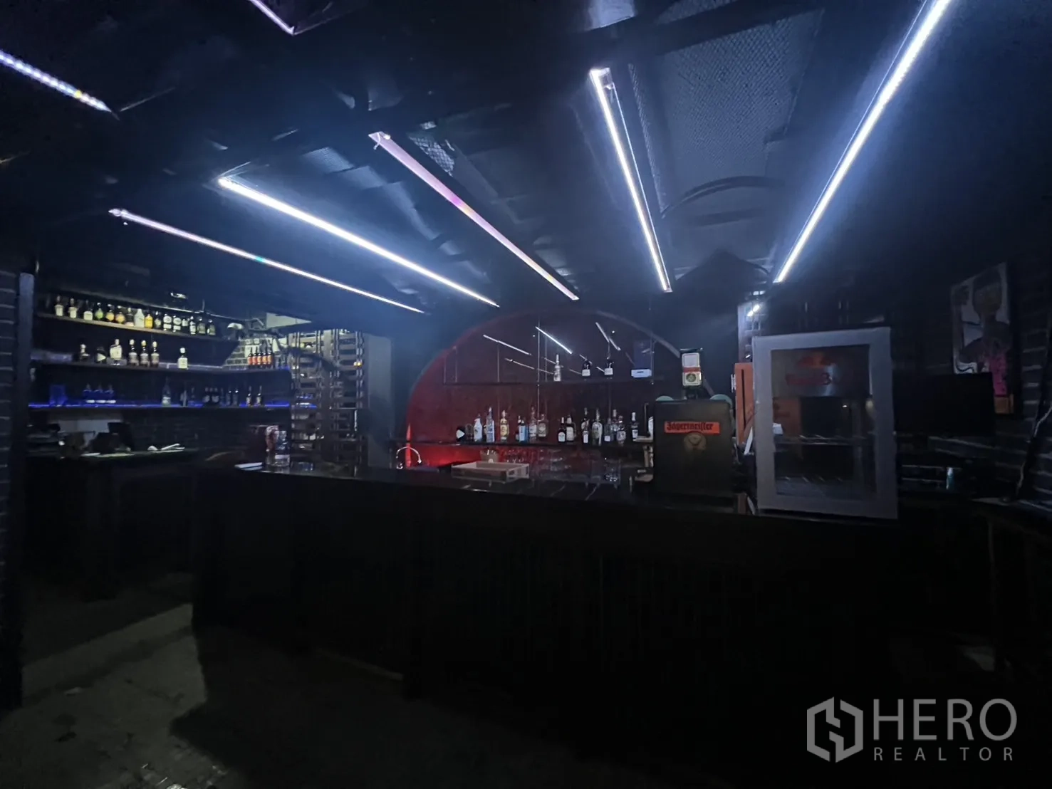 Retail Space for rent in Bangkok - Bar area with long counter, illuminated ceiling strips and bottle racks.
