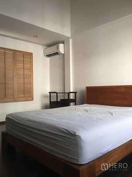 联排别墅 出租在Khlong Toei, Bangkok - 卧室内木床，壁挂机空调与百叶窗。