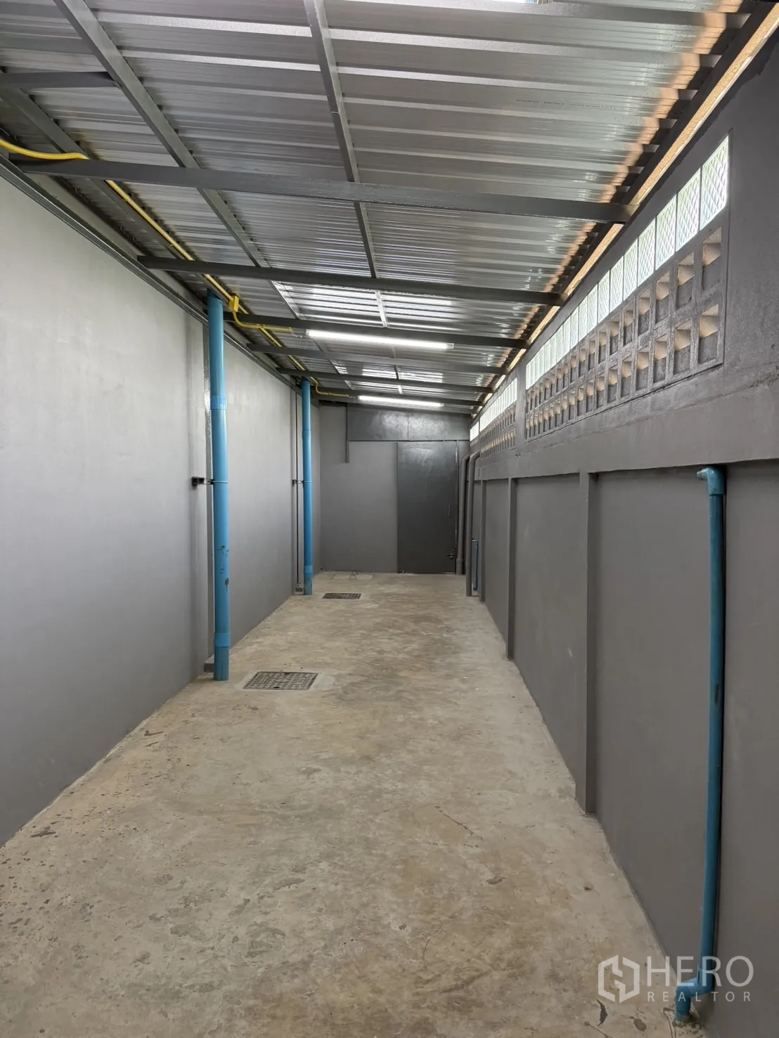 Warehouse for rent in Lam Luk Ka, Pathum Thani - Covered service corridor with drainage and utility pipes.