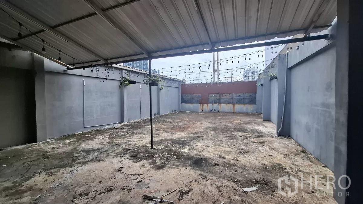 Shophouse for rent in Watthana, Bangkok - Rooftop terrace with partial metal roof and string lights, with city views beyond.