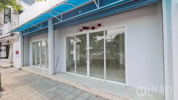 Shophouse for rent - White facade featuring full-height sliding glass storefront beneath canopy