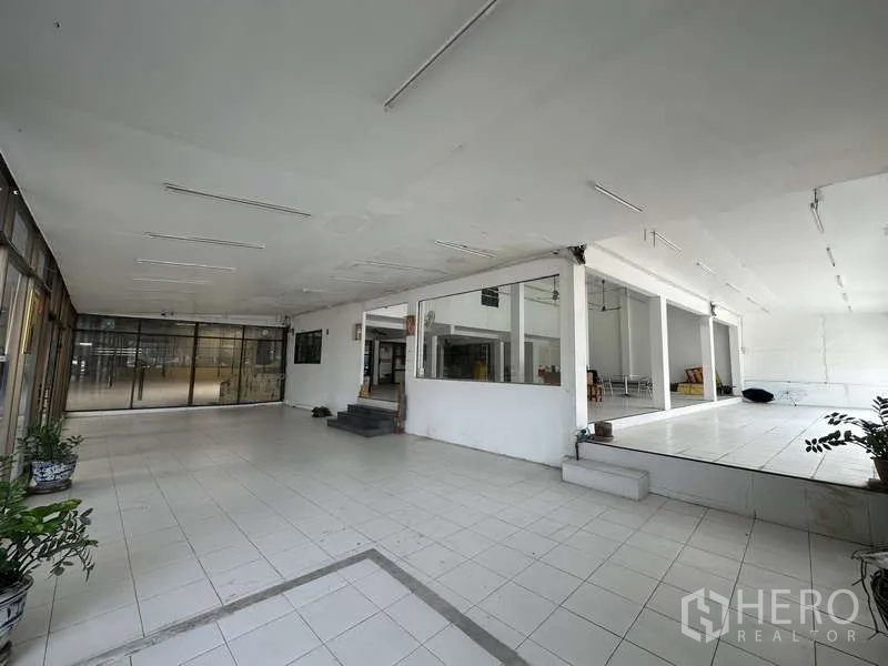 货栈 出租在Pak Kret, Nonthaburi - 可灵活布置的展陈区，带抬高平台、瓷砖与玻璃隔断。