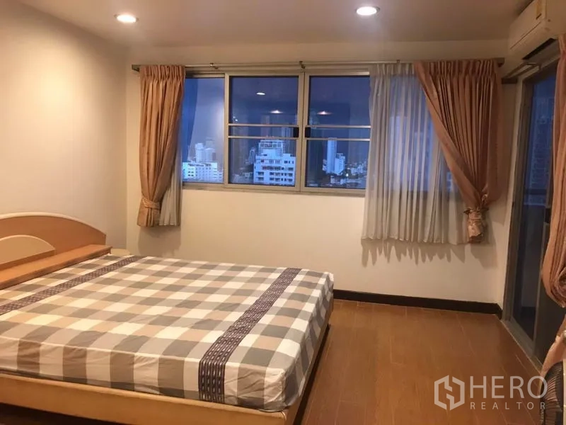 Condominium for rent or sale in Khlong Toei, Bangkok - Corner master bedroom with large windows, curtains and dusk city skyline views.
