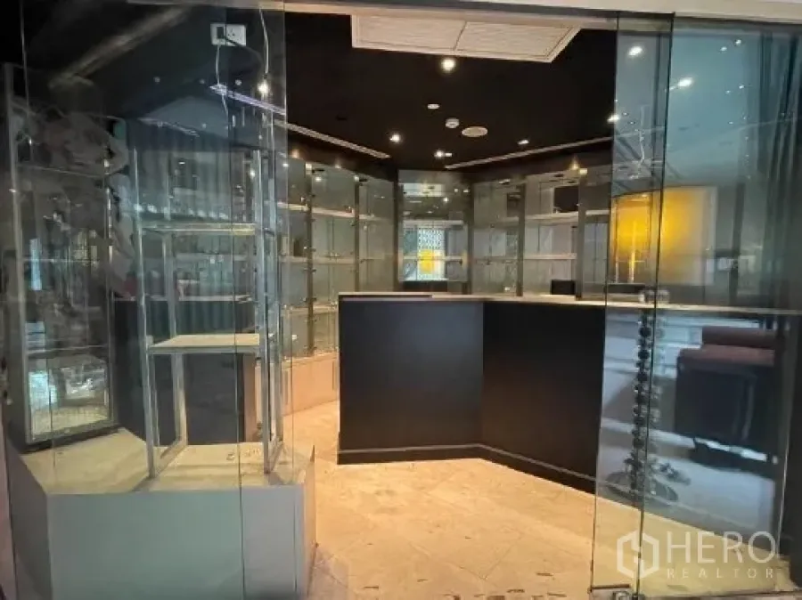 零售空间 出租在Watthana, Bangkok - 小型零售店内景，玻璃展示柜、黑色天花射灯与中央服务台。